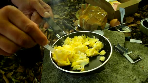 Cooking in nature on small camping cooker, scrambled eggs on pan for breakfast. Scrambling of small camping spatula on surface of non-stick frying pan. — Stock Video