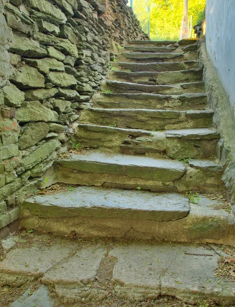 Open small steps at old building, old worn out stony steps behind house. Stony wall from raw boulders and concrete.