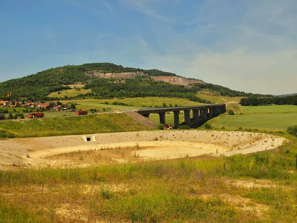 Bau einer neuen Autobahn, Abstreifer ändern Oberfläche oder Kies. Mann in kurzen Hosen geht. heißer, sonniger Sommertag. — Stockfoto