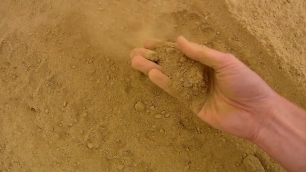 Pelle rosa mano alla ricerca di qualcosa in argilla polverosa estremamente secca. Vento delicato toglie polvere dal palmo della mano, polvere tra le dita, unghie sporche . — Video Stock