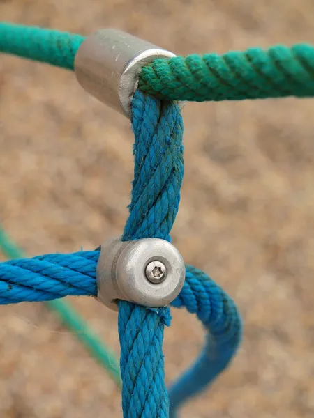 Point de joint de fer de cordes dans la toile d'araignée des enfants avec vis. Détail des cordes bleues croisées dans l'équipement extérieur d'escalade de sécurité . — Photo