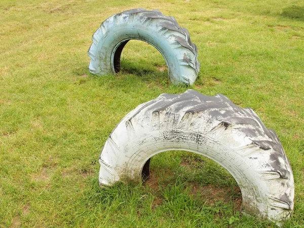 Dos neumáticos de camiones viejos en el suelo del patio de recreo . — Foto de Stock