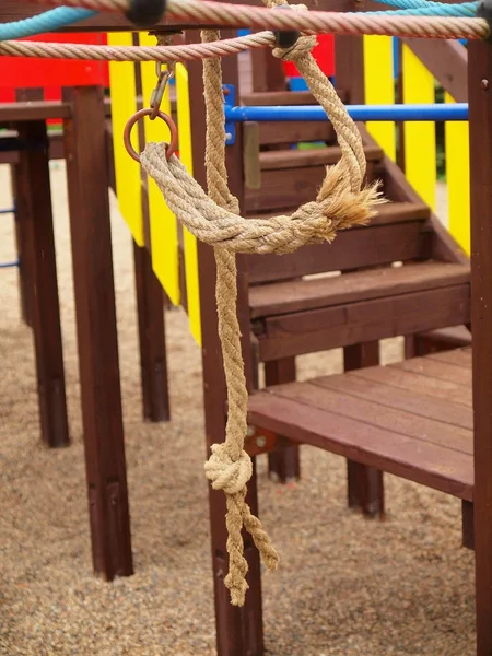 Wooden construction on kinder playground, twisted rope on hanger. — Stock Photo, Image