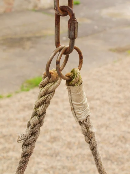 Fin de corde balançoire accrocher sur la construction en bois dans l'aire de jeux. Extrémité de corde rugueuse en cercles métalliques et crochet de sécurité . — Photo