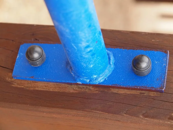 Wspólnego punktu dokręcania niebieskie rury stalowe i brązowy konstrukcji drewnianej. Detal połączenia drewniane belki i żelaznej rury w na zewnątrz urządzenia. — Zdjęcie stockowe