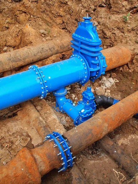 Old big drink water pipes joined with new blue valves and new blue joint members. Finished repaired piping waiting for covering by clay. Extreme kind of corrosion, metal corroded texture. — Stock Photo, Image