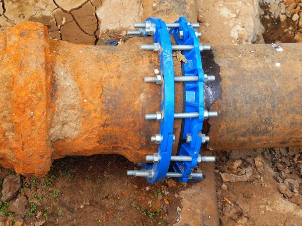 旧的大饮水管与新的蓝色螺丝接头连接。完成了修复后的管道, 等待粘土覆盖。极端类型的腐蚀, 金属腐蚀的纹理. — 图库照片