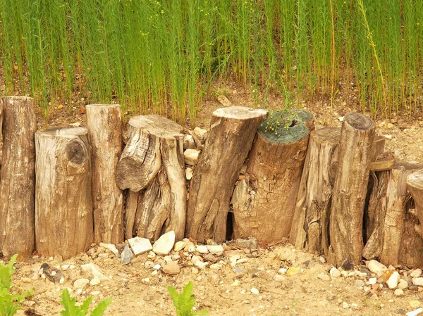 Oude houten palissade gemaakt van natuurlijke boomstammen, oude houten stockade, houten hek, stenige grond — Stockfoto