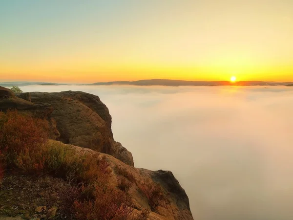 Pays d'automne. Vallée profonde et brumeuse, pleine de brouillard bleu orangé. Pics de grès augmentés par la brume, les collines sombres et le soleil jaune chaud à l'horizon . — Photo