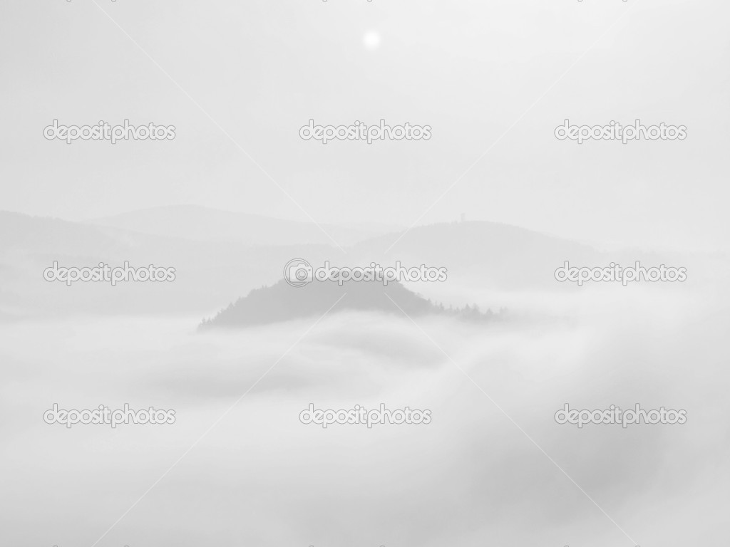 Misty dreamy landscape. Deep misty valley in autumn Saxony Switzerland park full of heavy clouds of dense fog. Sandstone peaks increased from foggy background