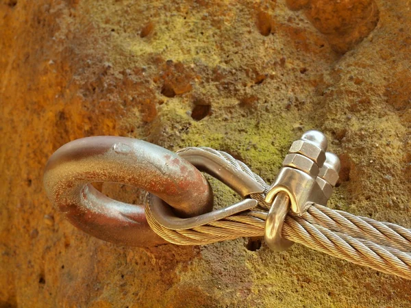 Detalle de cuerda anclada en roca arenisca. Cuerda retorcida de hierro fijada en percha de acero por tornillos ganchos a presión . — Foto de Stock