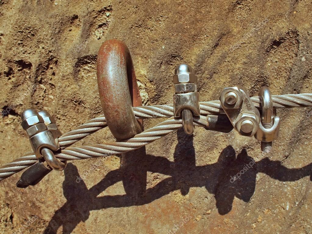 Detail of thin iron rope end anchored for climbers into sandstone rock