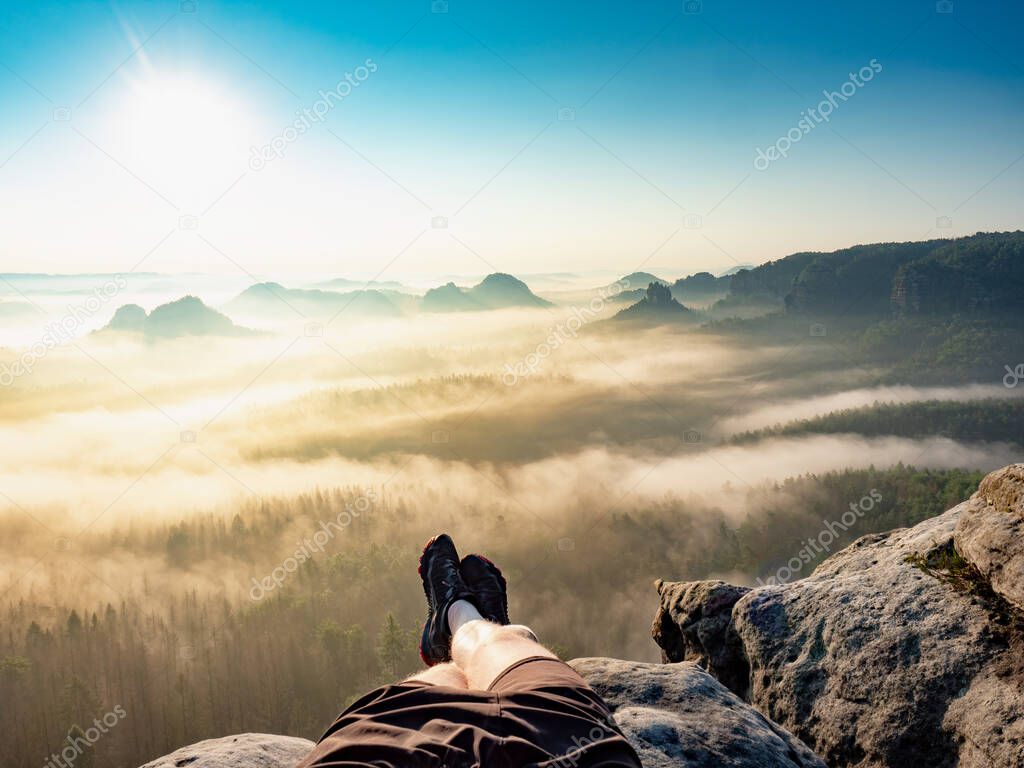 First person view to resting hiking legs,resting during hike. High rocks, clear sky and sun,