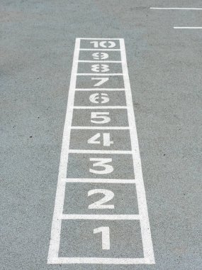 Başlangıçtan itibaren gri zeminde tebeşirle çizilen klasik Hopscotch oyunu