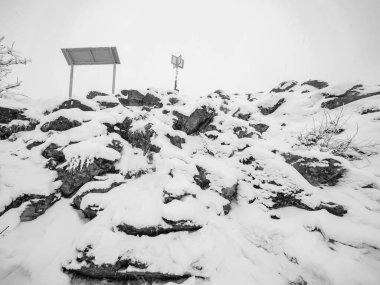 Taze toz kar ile kayalık araziye yakın, yoğun siste gizlenmiş manzara. Sisli kış günü. BW, Siyah ve Beyaz,