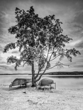 Gölde baş aşağı duran basit bir kayık. Popüler turizm merkezinin boş plajı. BW, Siyah ve Beyaz,