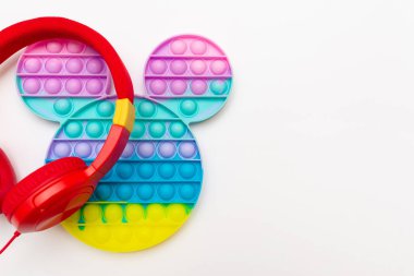 Moda silikon duyusal oyuncak antistresi patlat. Gökkuşağı stres önleyici oyuncak gerdanlığı ve beyaz arka planda kulaklık. Boşluğu kopyala.