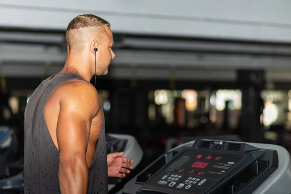 Young man in sportswear running on treadmill at gym.Handsome sport gym man running on the treadmill.Indoors shot.Man running in a gym on a treadmill.Healthy lifestyle concept.Copy space.