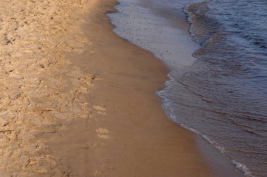 Kumlu sahilde denizin yumuşak dalgası. Odaklanma, bulanık görüntü. Boşluğu kopyala.