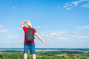 Orman manzarasına hayran olan genç bir adam. Arka planda vahşi ormanla birlikte yaz günü tek başına ayakta duran genç bir adam. Seyahat yaşam tarzı kavramı arka görünümü
