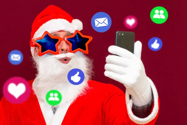 圣诞老人引起了社交媒体的注意 圣诞老人带着眼镜 在他的手机上使用不同的应用社交媒体服务 — 图库照片