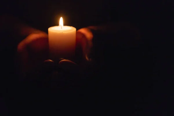 在黑暗中像心一样握住燃烧的蜡烛的手 有选择的焦点 黑色背景 复制空间 — 图库照片