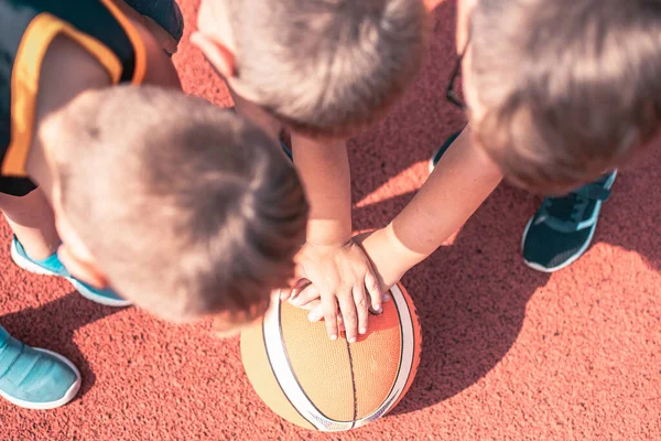 Three Kids Basketball Team. Young Basketball Players Holding Ball on red Basketball Court. Basketball Horizontal Background.