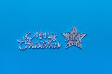 Mavi arka planda duran mutlu noel yazıları yıldızı. Kış tatili hediye kartı..