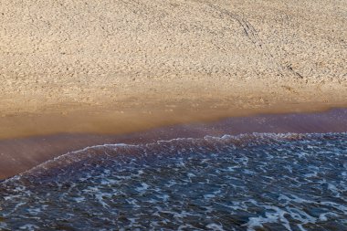 Kumlu sahilde denizin yumuşak dalgası. Odaklanma, bulanık görüntü. Boşluğu kopyala.
