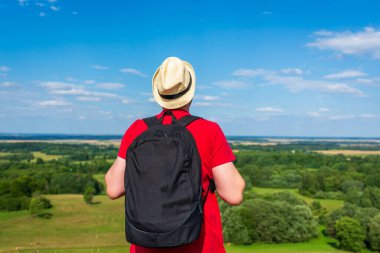 Orman manzarasına hayran olan genç bir adam. Arka planda vahşi ormanla birlikte yaz günü tek başına ayakta duran genç bir adam. Seyahat yaşam tarzı kavramı arka görünümü