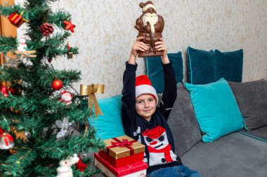 Kanepede oturan çocuk hediyesini kaldırıyor Noel Baba 'nın hediyeleri, elinde hediyeler..