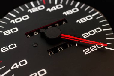 Araba hız göstergesi. Otomobil hız göstergesi 220 km / s gösteriyor. Yakın çekim, koyu siyah arkaplan. Tehlikeli hız kavramı