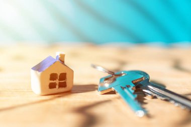 Minyatür yeni ev anahtarları ahşap mavi arka plan, gayrimenkul ve emlak işi kavramı. Kapanış, seçici odaklanma..