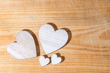 Farklı boyutlarda dört tahta kalp kahverengi ahşap bir arka planda yatıyordu. Sevgi, aile ve sevgililer günü kavramı. Boşluğu kopyala..