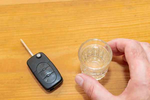 Drunk driving - the cause of car accidents. Hand reaches for car key and alcohol.Drink. Male hands and auto keys.