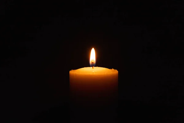 在黑色的背景里 一根光的蜡烛在明亮地燃烧着 黑暗中的烛焰 复制空间 — 图库照片