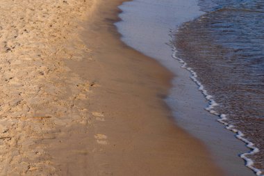Kumlu sahilde denizin yumuşak dalgası. Odaklanma, bulanık görüntü. Boşluğu kopyala.