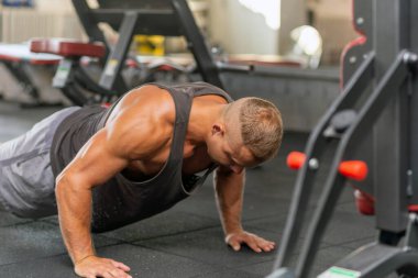 Şınav çeken genç sporcu. Spor salonunda egzersiz yapan kaslı ve güçlü bir adam. Spor kıyafetli genç yakışıklı bir adamın spor salonunda şınav çekmesi..
