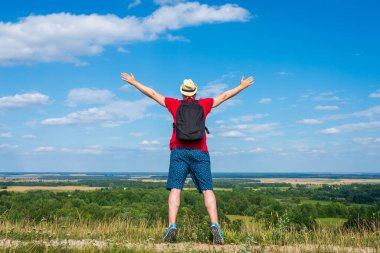 Orman manzarasına hayran olan genç bir adam. Arka planda vahşi ormanla birlikte yaz günü tek başına ayakta duran genç bir adam. Seyahat yaşam tarzı kavramı arka görünümü