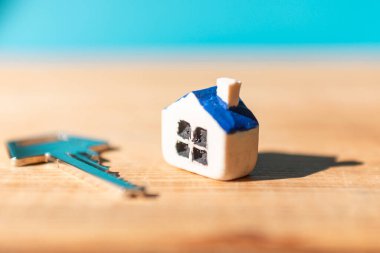 Ahşap mavi arka planda ev anahtarı olan minyatür yeni bir ev, gayrimenkul ve emlak işi kavramı. Kapanış, seçici odaklanma..