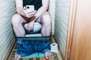 Tuvalette otururken akıllı telefon kullanan ya da cep telefonuyla mesajlaşan bir adam. Sağlıklı bir kavram..