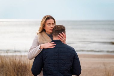 Baharda plajda genç ve şık bir çift. Birbirinize sarılın ve sıcak bir bahar akşamının tadını çıkarın..