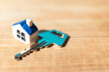 Ahşap arka planda ev anahtarı olan minyatür yeni bir ev, emlak ve emlak işi kavramı. Kapalı, seçici odaklı..