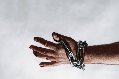 Erkek eli çelik bir zincir içinde. Çelik zincirler, gri bir duvardaki adamın elinde. Tonlama. Yaklaş, seçici odaklanma..