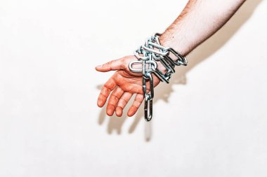 Zincirli el, alttan sarkan zincir, gri arka plan. Boşluğu kopyala, seçici odaklanma..