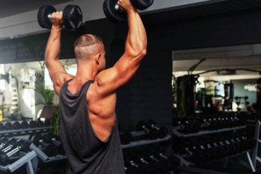 Spor salonunda aptal gibi egzersiz yapan genç ve formda bir adam. Sağlıklı bir adam aptallarla çalışıyor. Kapalı alanda çekim yapıyor..