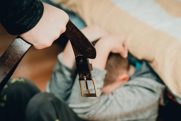 家庭暴力和攻击性观念 愤怒的男人在家里用皮带对着吓坏了的孩子举起了惩罚的拳头 — 图库照片