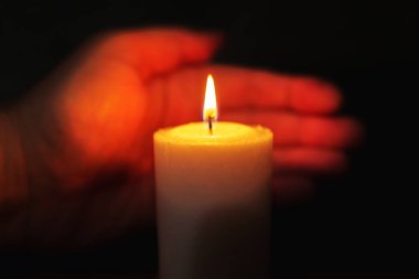 Bir avuç içi mum yangınıyla gece ilgilenir. Seçici odak, koyu siyah arkaplan. Yaklaş..