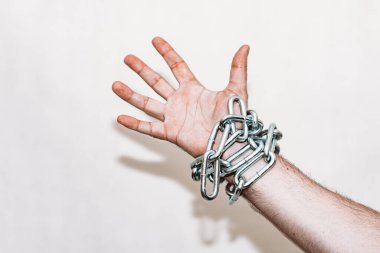 Zincirli el, alttan sarkan zincir, gri arka plan. Boşluğu kopyala, seçici odaklanma..