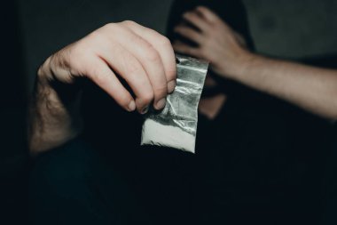 Uyuşturucu dolu plastik poşet taşıyan bir suçlu. Elinde şeffaf plastik bir torba tutan bir adam. Uyuşturuculu kavramsal suçlu. Yakından, seçici odaklı, uyumlu..